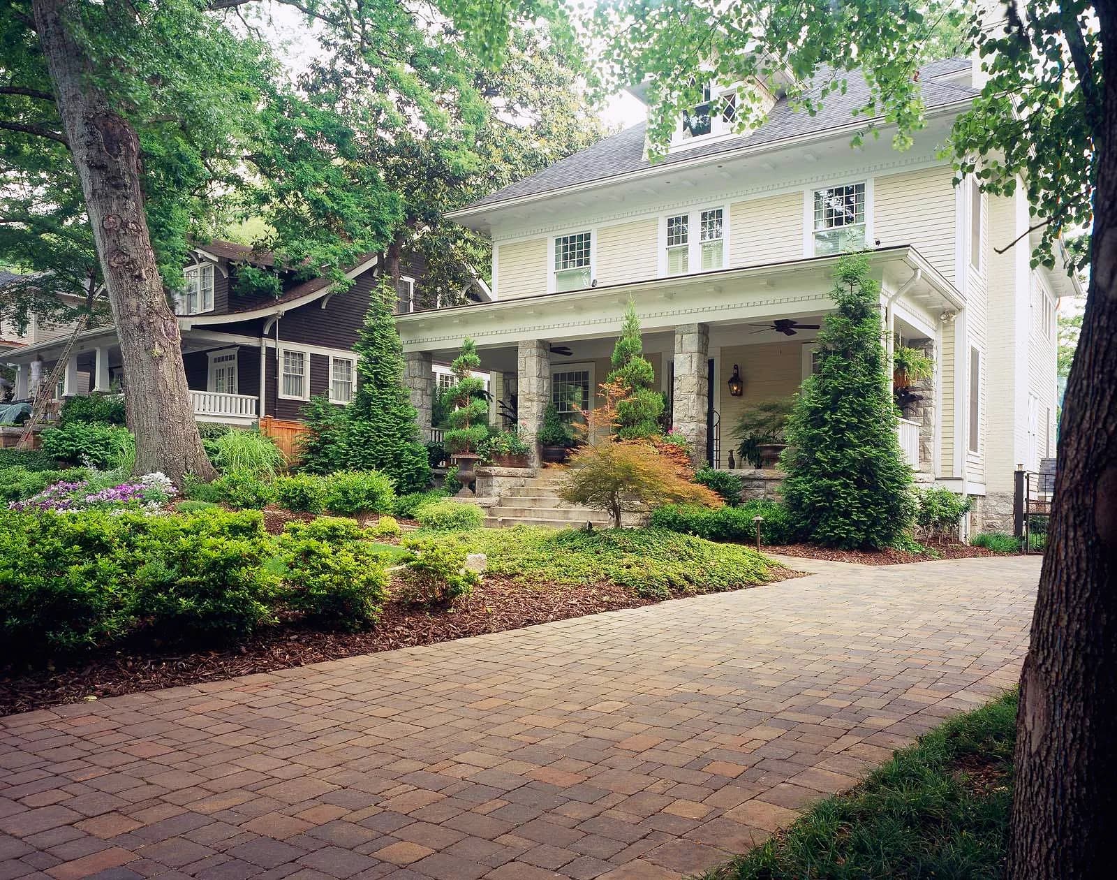 Brick paver driveway leading to a white two-story house